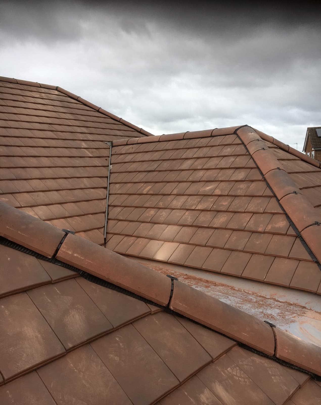 Clay tiled roof completed by Delapre Roofing in Corby under a dramatic sky